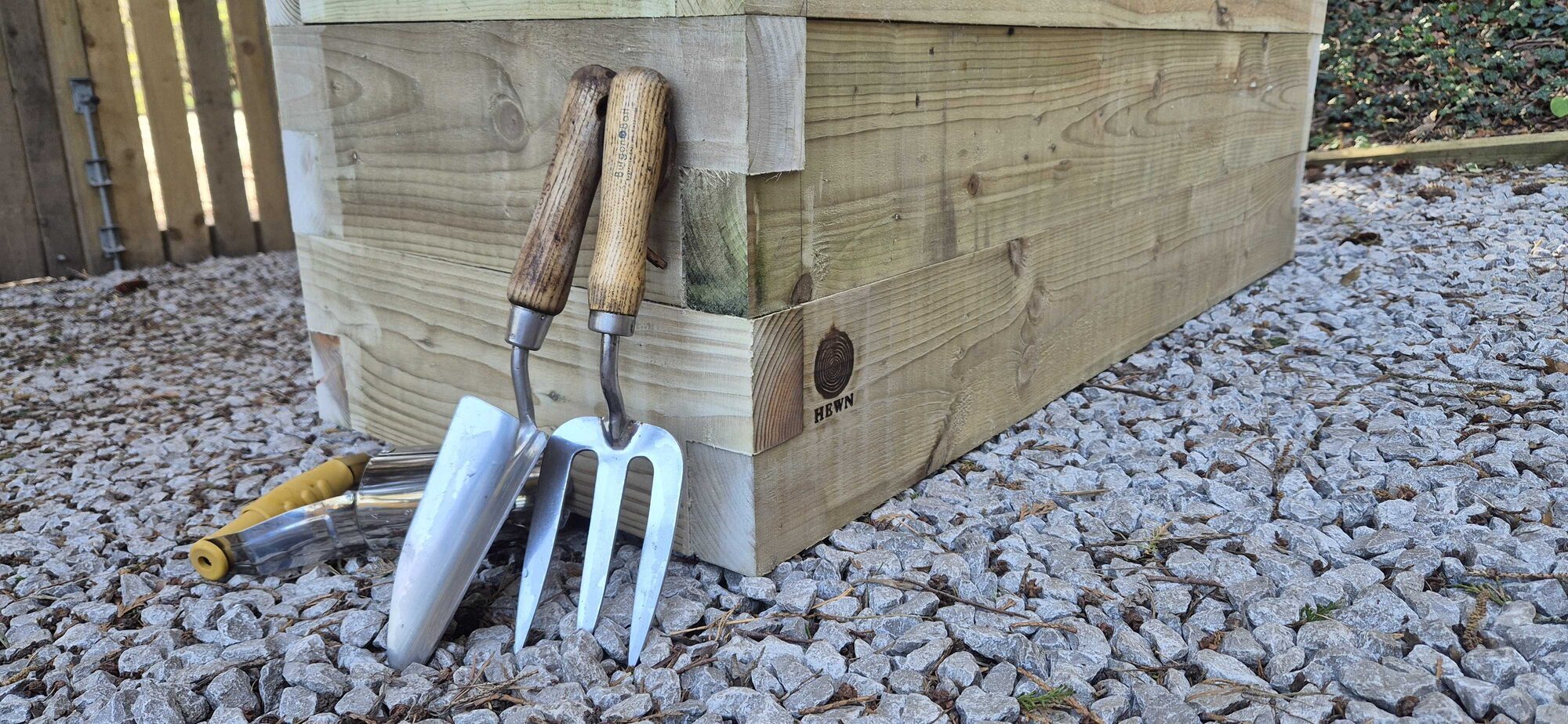 The HEWN maker's mark burned into the corner of a handmade wooden planter, with hand tools