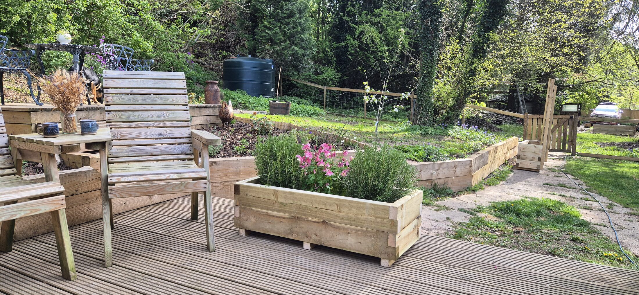 A handmade HEWN wooden planter in a planted North Wales garden